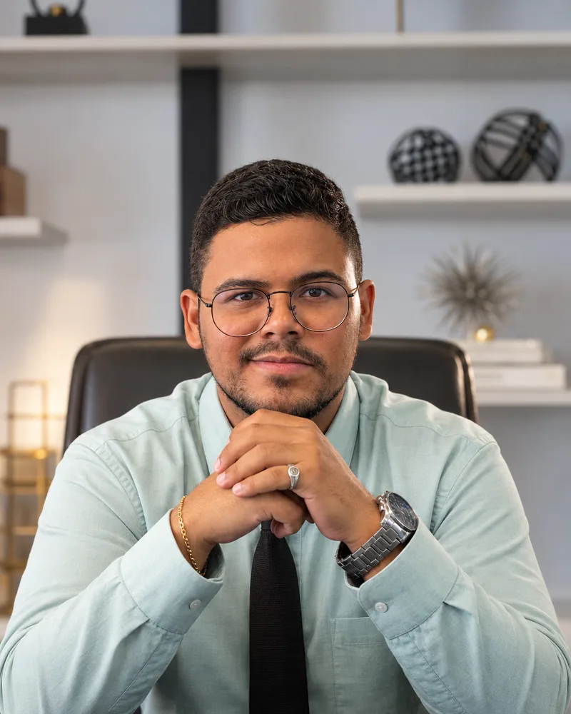Dr. Caio Ramon Flores sentado à mesa do escritório, sorrindo